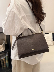 Sac bandoulière vintage en cuir marron foncé avec fermoir doré porté par modèle