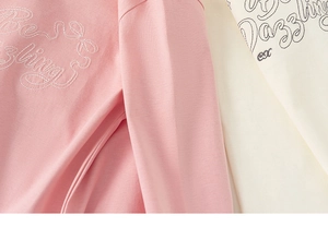 Detail von Mädchen-Strickshirts mit hochwertiger Stickerei und bedruckten Buchstaben