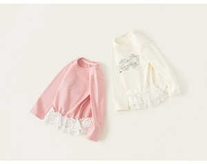 Detail eines Langarmshirts für Mädchen mit Spitzenbesatz am Saum und gestickter Aufschrift