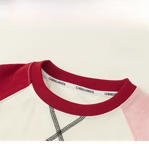 Close-up of kids' round neck raglan t-shirt with red ribbing and cross stitching details