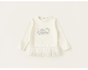Detail eines cremefarbenen Langarmshirts mit Be Dazzling-Aufdruck und Spitzenbesatz