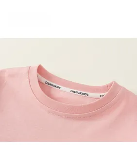 Detailansicht des Rippbündchen-Ausschnitts und Markenbands am rosa Baumwollshirt
