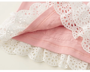 Makroansicht aus rosa Strickstoff mit weißer Lochstickerei und verstärkten Nähten am Saum