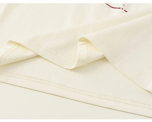 Close-up of girls raglan shirt hem showing neat double-needle stitching on beige cotton