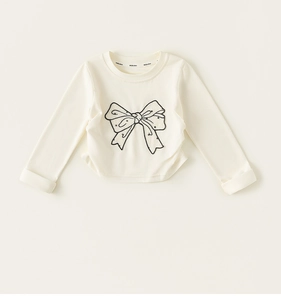 Gros plan d'imprimé nœud noir sur t-shirt à manches longues en coton crème pour filles