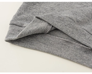 Nahaufnahme von grauem Strickstoff mit geripptem Saum und feinen Nähten an der Kleidung