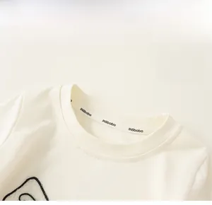 Vue détaillée du col rond à double couture et de la bande de renfort intérieure du t-shirt blanc en coton
