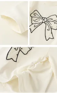 Détail du haut en coton blanc avec nœud à pois et ourlet plissé au design délicat