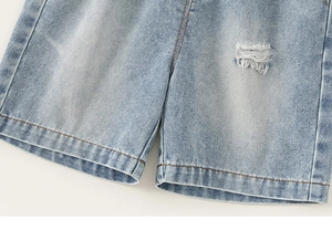 Detail of light blue denim shorts featuring distressed ripped hem and washed texture