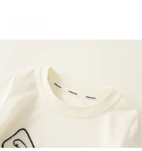 Détail du col rond en coton blanc avec ruban logo à l'intérieur de l'encolure