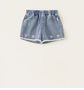 Detail of girl's denim shorts with elastic waist, lace trim, and pink heart embroidery