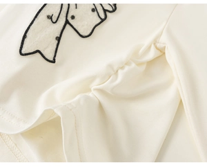 Gros plan détaillé d'un haut en tricot crème pour fille avec applique girafe 3D et fronces