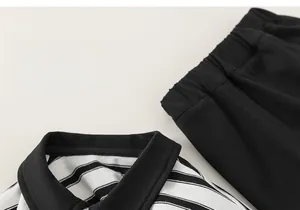 Detail of kids striped polo shirt and black elastic waist shorts set on beige background