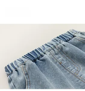 Detail of light blue denim shorts featuring elastic waistband and orange topstitching