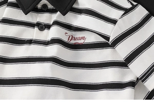 Close-up of black and white striped kids polo shirt with red Dream embroidery detail