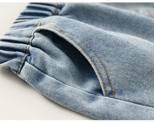 Detail of light blue denim shorts with elastic waistband and orange stitching accents
