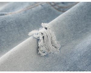 Detailed macro view showing ripped distressed denim fabric with frayed white fiber texture
