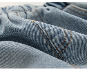 Detail of light blue denim fabric with elastic waistband and sturdy yellow stitching