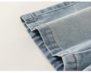 Detail of light blue denim fabric with reinforced orange double stitching on the hemline