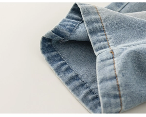 Macro view showing high-quality contrast orange stitching on light blue denim shorts hem
