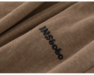 Détail du tissu marron de qualité avec broderie noire INSbobo et texture très raffinée