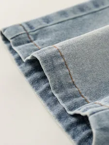 Close-up of light blue kids denim shorts hem with durable orange contrast stitching detail