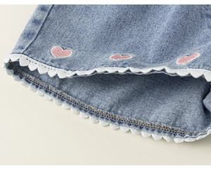 Detail of girls' denim shorts with pink heart embroidery and white scalloped lace edge