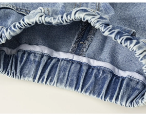 Detailed close-up of girls' blue denim shorts showing elastic waistband and stitching