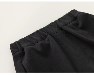 Detail of children's black cotton pants featuring an elastic waistband and neat stitching