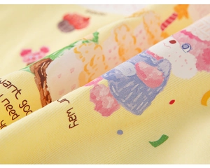 Close-up of soft yellow cotton ribbed fabric with cute bear and cupcake cartoon prints
