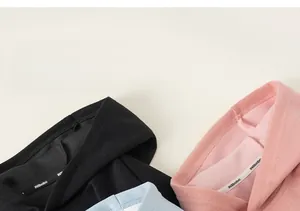 Détail de sweats à capuche doux avec bande de col de marque en noir, rose et bleu clair