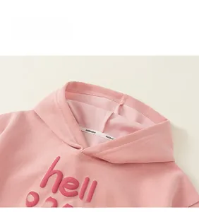 Détail d'un sweat à capuche rose pour enfant avec lettrage 3D en relief et ruban de col