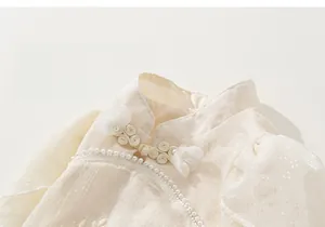 Detailaufnahme des Kinder-Cheongsam-Kleids mit Perlenbesatz und Knopfverschlüssen