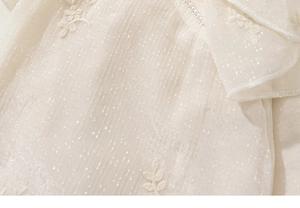 Detailansicht eines Kinder-Qipao-Kleides mit Perlenbesatz und floraler Stickerei