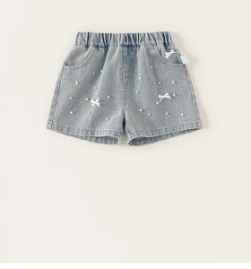 Dettaglio degli shorts in denim azzurro da bambina con fiocchi bianchi e perline
