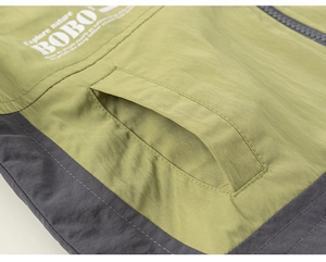 Detail der Outdoor-Kapuzenjacke mit grünem Windbreaker-Stoff und Taschennaht