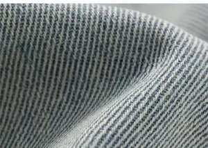 Primo piano del tessuto denim blu che mostra la trama a saia e la morbida fibra naturale