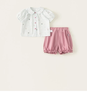 Detail of baby girl summer outfit with cartoon print shirt and pink ruffle shorts