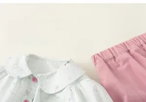 Detail of baby girl summer set featuring cartoon plaid shirt and pink shorts