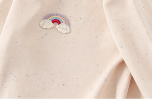 Détail d'un t-shirt en coton pour fille avec broderie arc-en-ciel et texture côtelée