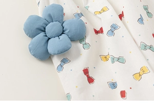 Nahaufnahme der blauen Stoffblume auf weißem Kleid mit Schleifen- und Punktemuster