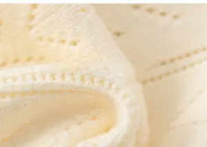 Detailaufnahme von cremefarbenem Strickstoff mit Lochmuster und weicher Textur