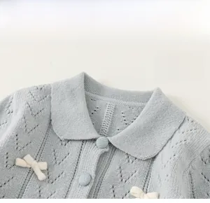 Detailaufnahme der blauen Kinderstrickjacke mit Reverskragen, Schleifen und Lochstrickmuster