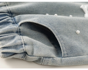Dettaglio ravvicinato di pantaloncini in denim azzurro con perle e vita elastica morbida
