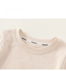 Détail du haut bébé en tissu confettis avec broderie arc-en-ciel colorée et encolure côtelée