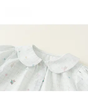 Detail of baby girl's plaid shirt showing Peter Pan collar and cute cartoon bear prints