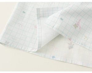 Detail of soft white fabric with blue grids and pink bunny prints on a baby outfit