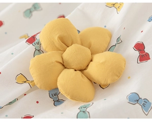 Detail einer gelben 3D-Stoffblume und bunte Schleifenmuster auf einem Baumwollkleid