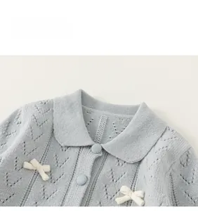 Detailaufnahme der blauen Strickjacke für Mädchen mit Puppenkragen und weißen Schleifen