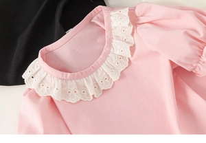 Detail of pink cotton shirt featuring delicate white lace collar and fine stitching